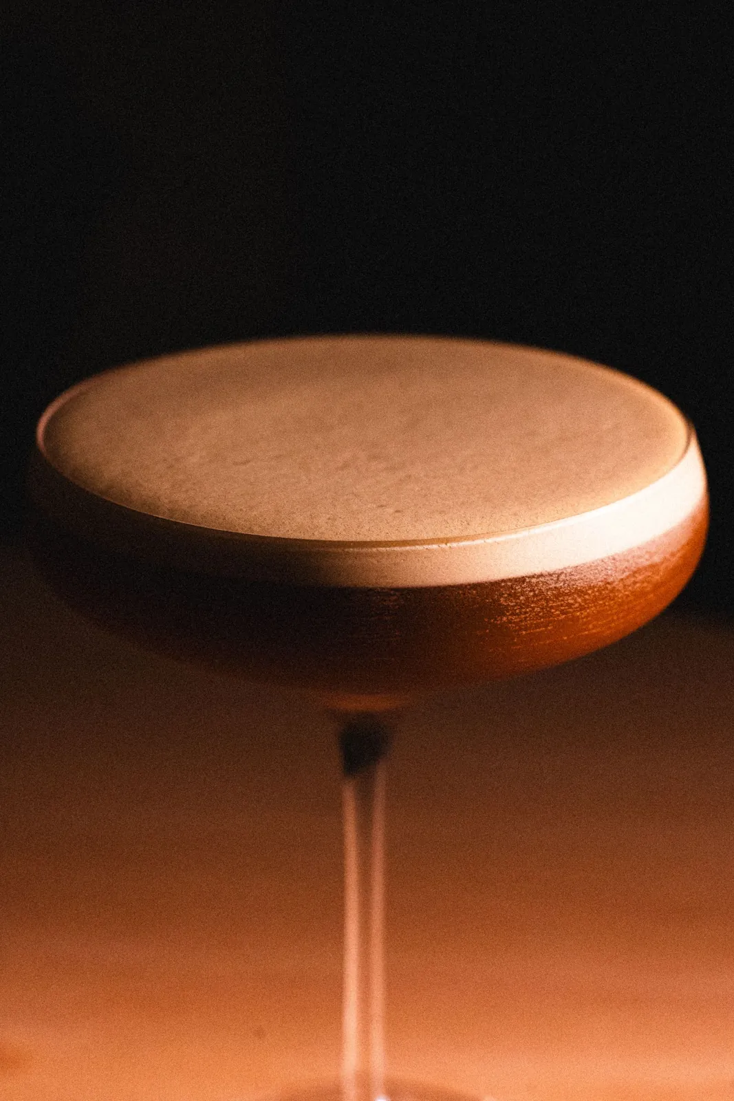 A frothy cocktail on the dark bar