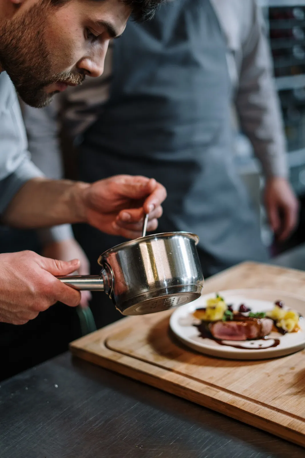 A plate being finished with sauce at the pass